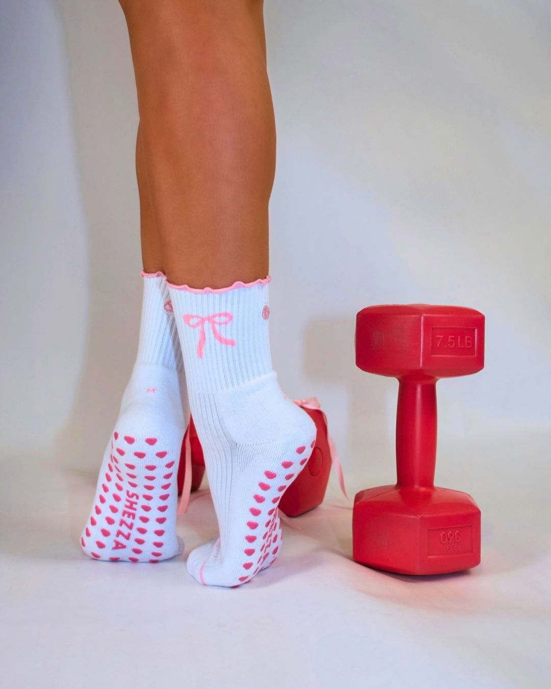 White Pilates grip socks worn beside red dumbbells