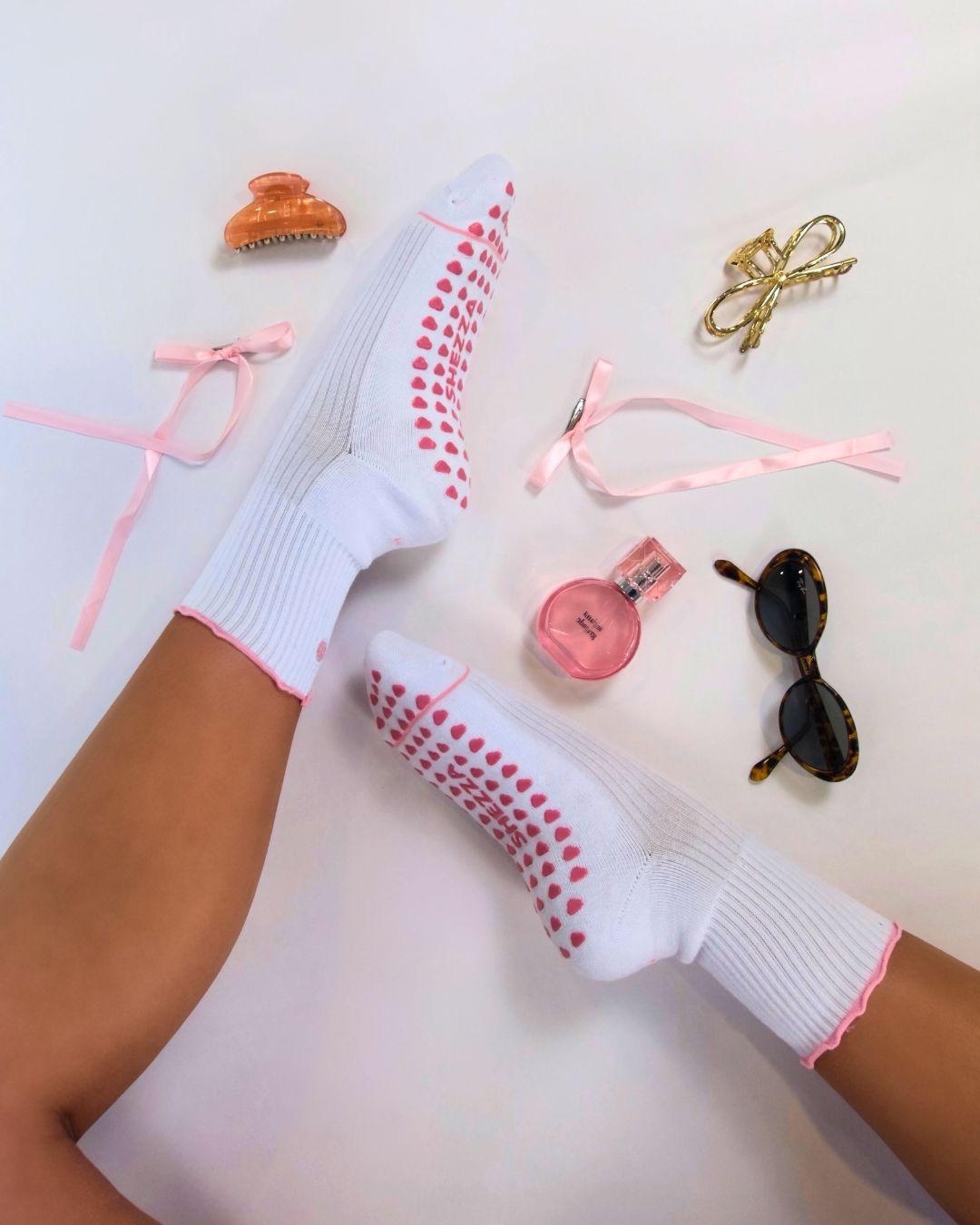 Close-up of white Pilates grip socks with pink trim and bow detail