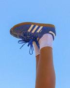 White Shezza sock worn with a blue Adidas Samba sneaker against a blue sky