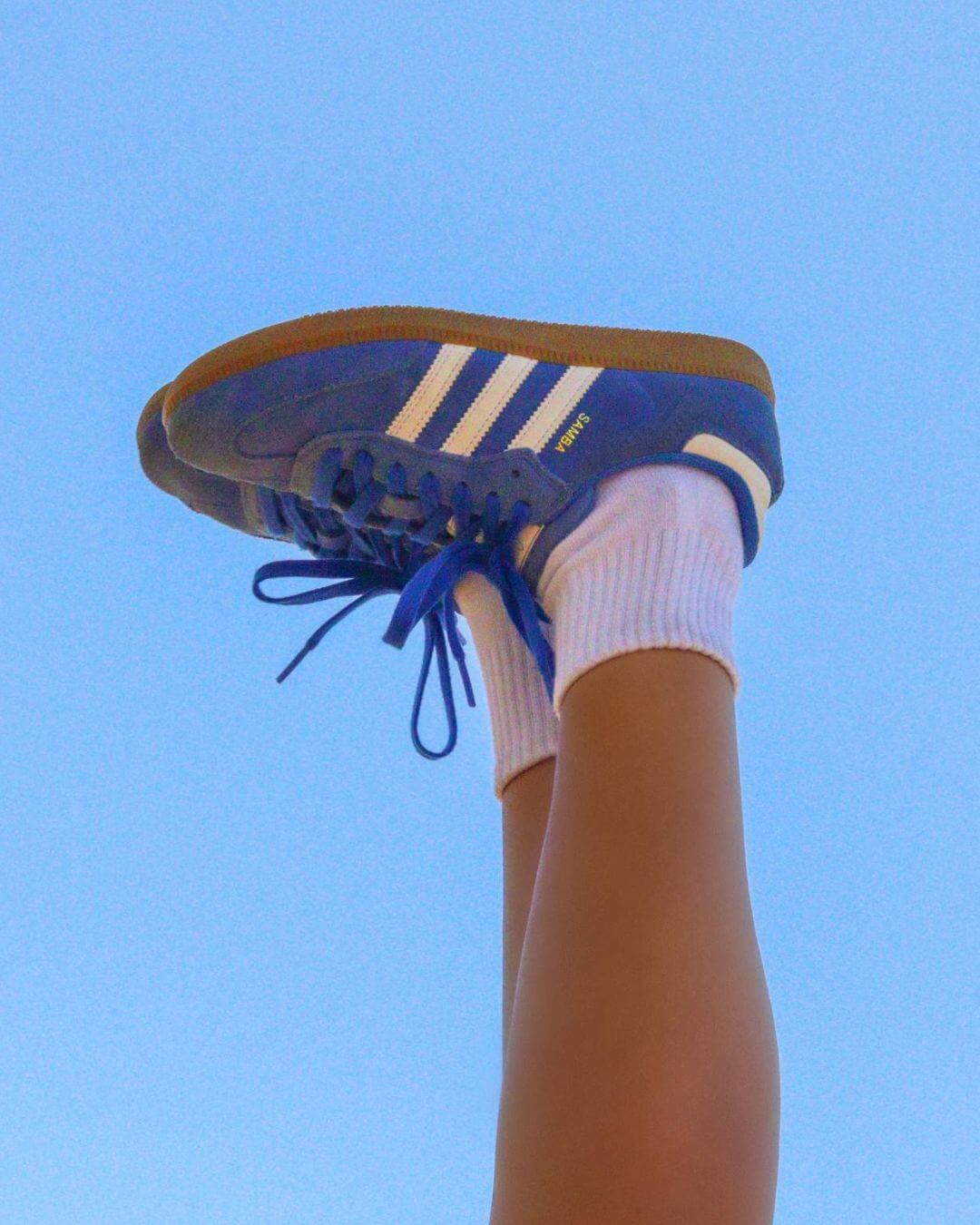 White Shezza sock worn with a blue Adidas Samba sneaker against a blue sky