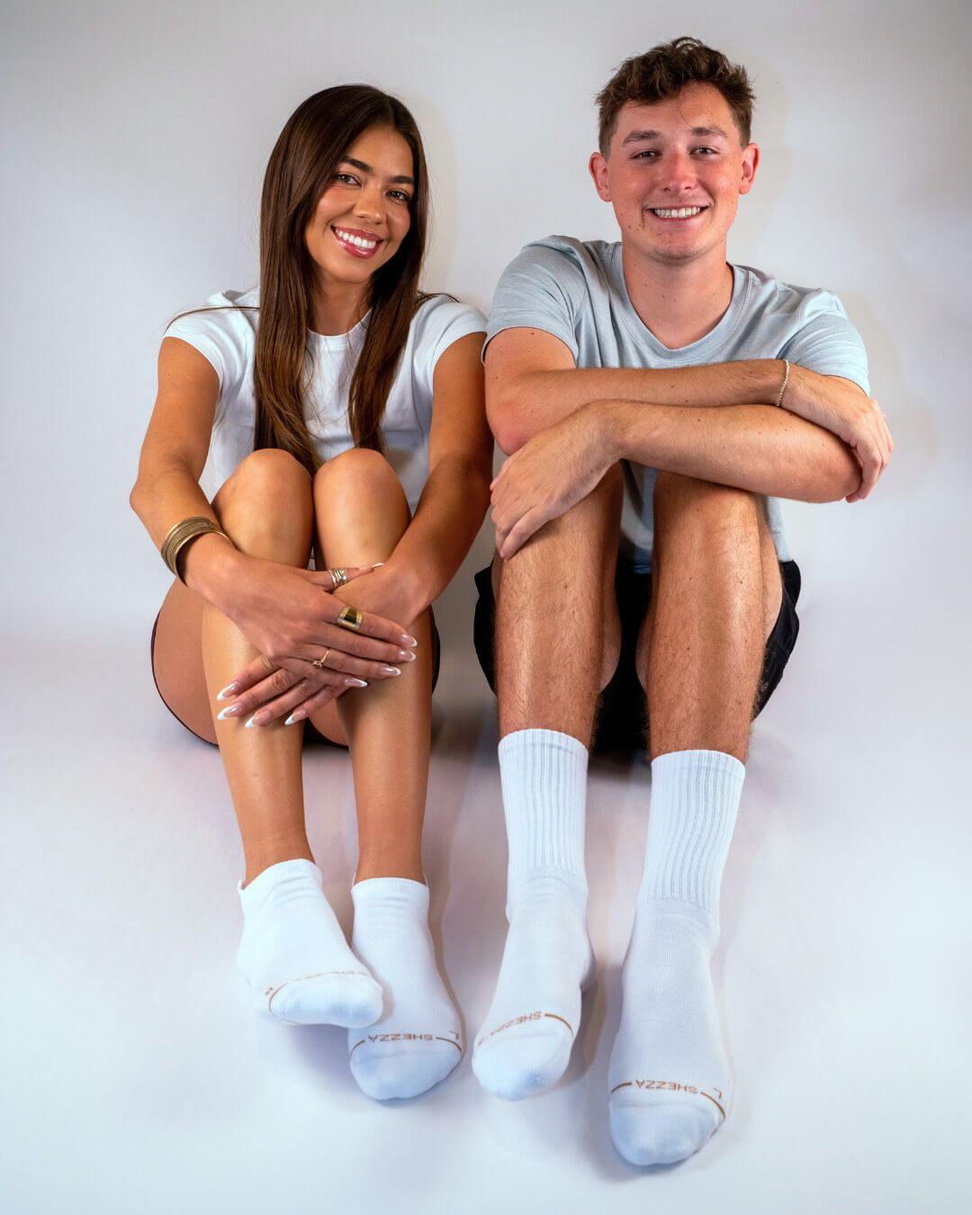 Couple seated together wearing white Shezza unpadded crew socks