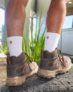 Legs in hiking boots and white padded crew socks on grass
