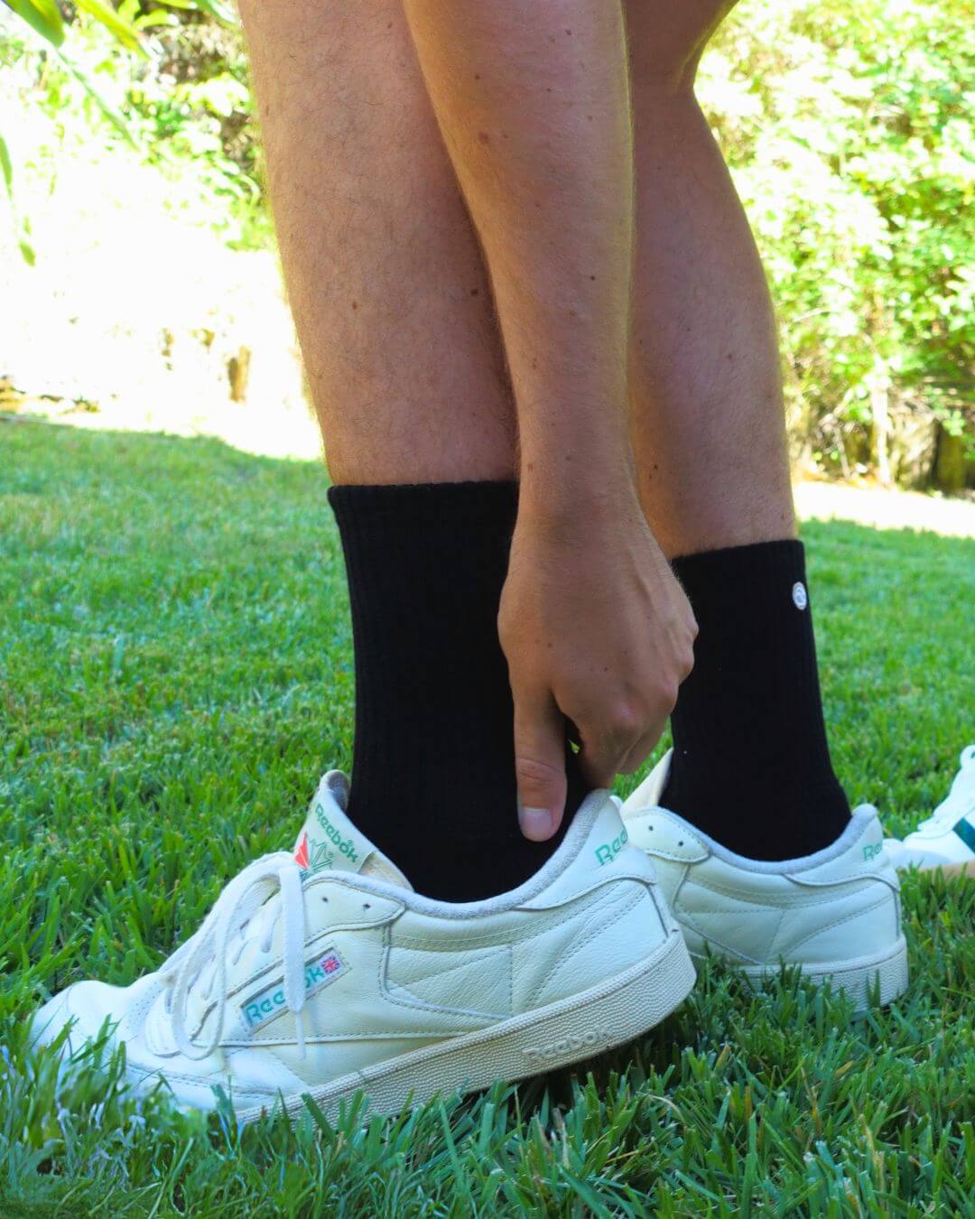 Black padded crew socks worn with white trainers on grass
