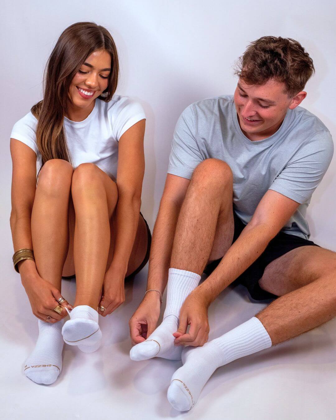 Man and woman seated side by side wearing white Shezza unpadded ankle socks
